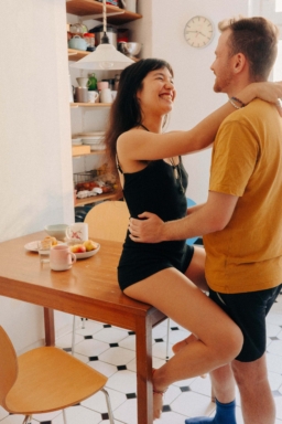 Frau sitzt auf Tisch und umarmt Partner